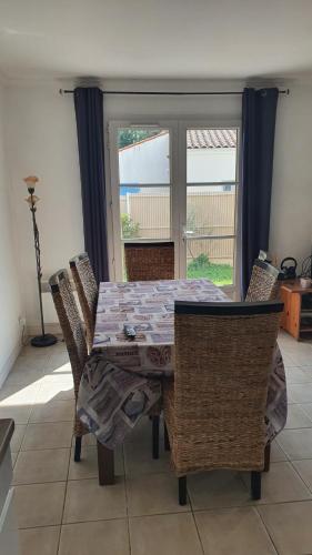 une salle à manger avec une table et des chaises et une fenêtre dans l'établissement Jolie maison au calme jardin plage a proximité, à Meschers-sur-Gironde