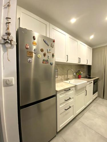 - un réfrigérateur en acier inoxydable dans une cuisine avec des placards blancs dans l'établissement Les Jades, au Cannet