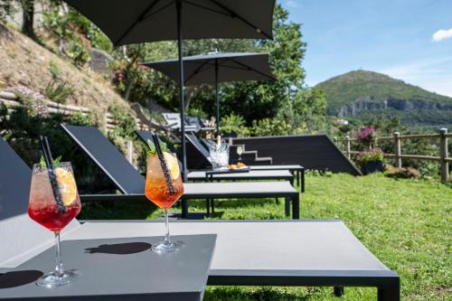 two glasses of drinks on a table under an umbrella at Kemì Luxury Suites in Vietri sul Mare