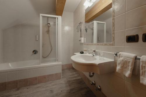 a bathroom with a sink and a shower and a tub at Hotel Alpenrose in Carezza al Lago