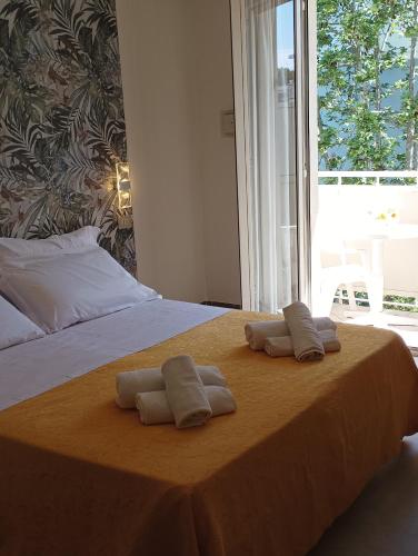 two towels on a bed with a large window at Hotel CARLO in Riccione