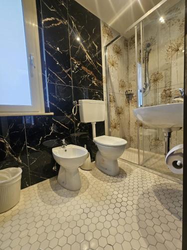 a bathroom with two toilets and a sink and a tub at Hotel CARLO in Riccione