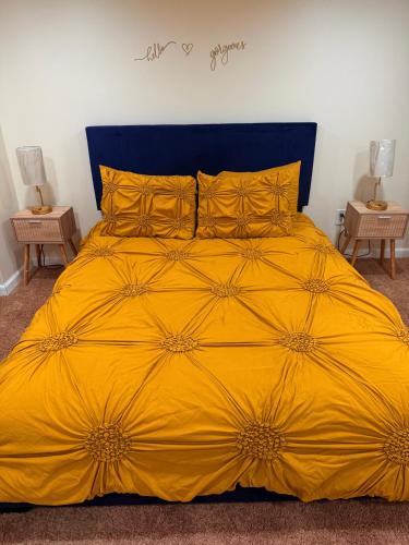 a yellow bed with a blue headboard and yellow pillows at Private Guest House-Lake Ronkonkoma in Ronkonkoma