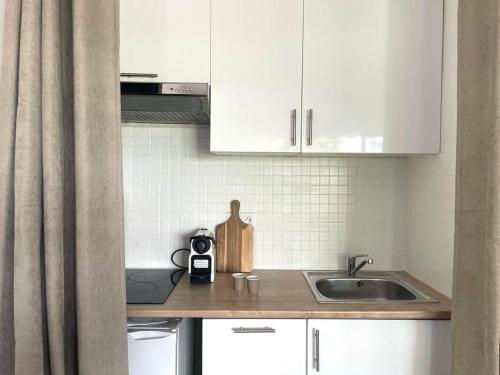 une cuisine avec des armoires blanches et un évier dans l'établissement Studio chic, Cannes Croisette 10 min, au Cannet