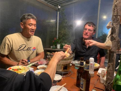 a group of men sitting around a table eating food at Guest House Isa in Motobu