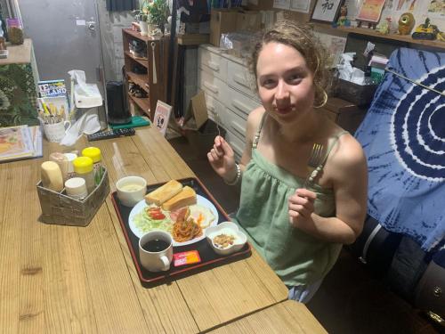 a woman sitting at a table with a plate of food at Guest House Isa in Motobu