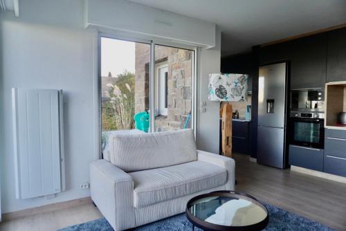 un salon avec un canapé blanc et une table dans l'établissement Beautiful apartment with sea and garden view, à Perros-Guirec