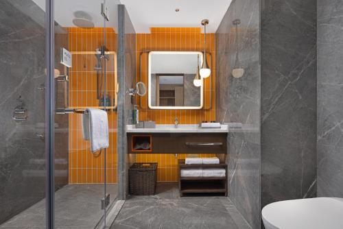 an orange bathroom with a sink and a mirror at Home2 Suite by Hilton Hengshui Taocheng in Hengshui