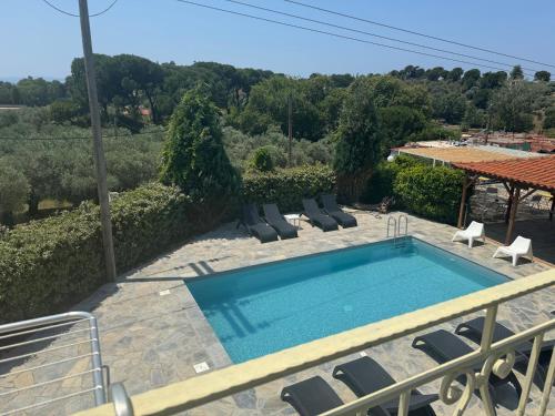 a swimming pool in a yard with chairs around it at Esperos Apartments&Studios in Troulos