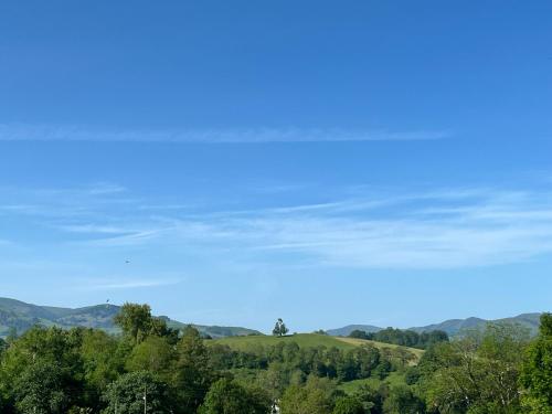 a blue sky with trees and mountains in the background at Ongi Etorri Chez les Ch'tis in Saint-Jean-le-Vieux
