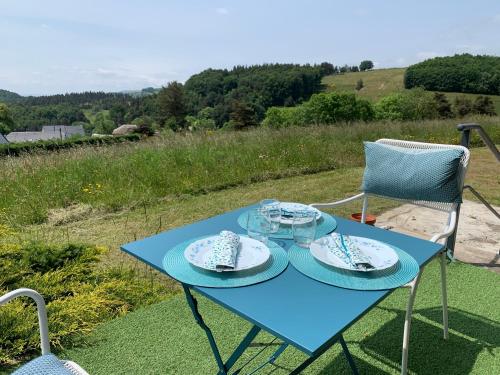 a blue table and chairs with plates and glasses on it at belle vue in Saint-Sauveur-de-Peyre