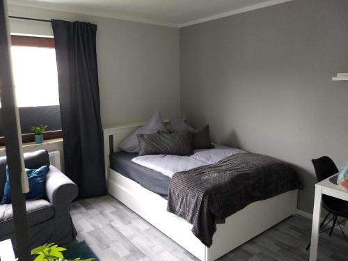 a bedroom with a bed and a chair and a window at City-Apartment in Bremerhaven in Bremerhaven