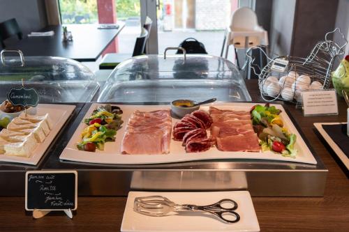 a counter with two plates of meat and vegetables at L'Hôtel et Restaurant du Golf de Clervaux in Eselborn