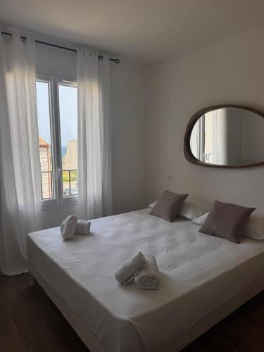 une chambre avec un grand lit blanc avec un miroir dans l'établissement Appartement neuf, proche des plages et centre ville, à Saint-Florent