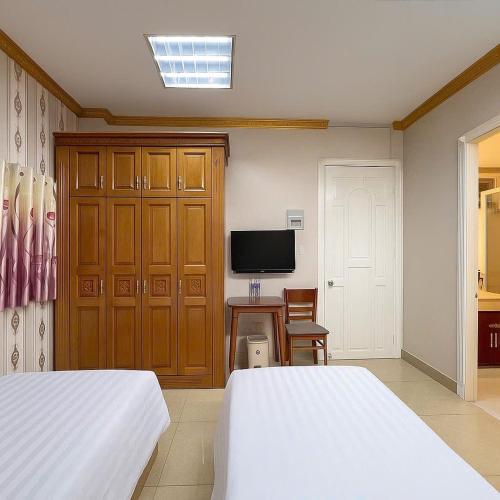 a bedroom with two beds and a tv and a desk at LuxuryK&T Hotel-Near Bùi Viện Walking Street in Ho Chi Minh City