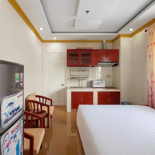 a bedroom with a white bed and a kitchen at LuxuryK&T Hotel-Near Bùi Viện Walking Street in Ho Chi Minh City