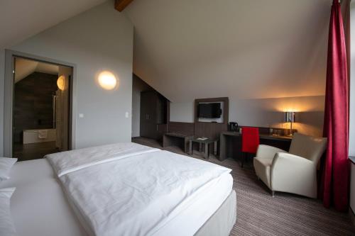 a hotel room with a white bed and a desk at L'Hôtel et Restaurant du Golf de Clervaux in Eselborn