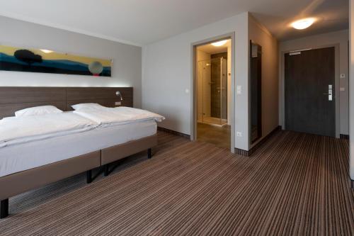 a bedroom with a large bed and a hallway at L'Hôtel et Restaurant du Golf de Clervaux in Eselborn