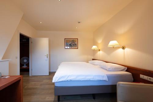 a bedroom with a large white bed with two pillows at L'Hôtel et Restaurant du Golf de Clervaux in Eselborn
