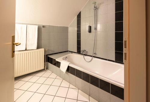 a bathroom with a bath tub and a shower at L'Hôtel et Restaurant du Golf de Clervaux in Eselborn