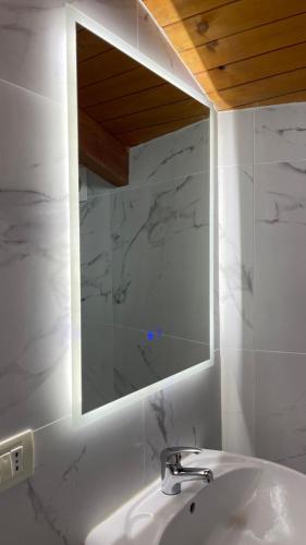 a white bathroom with a sink and a mirror at Bellway Hotel in Shkodër