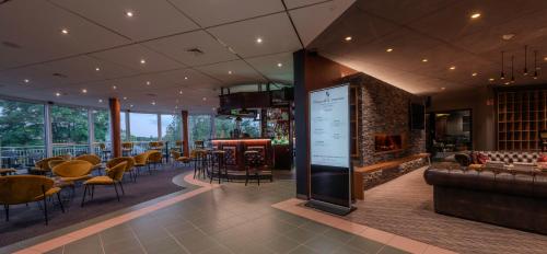 a restaurant with a bar with a fireplace and chairs at L'Hôtel et Restaurant du Golf de Clervaux in Eselborn
