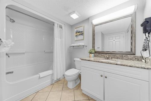 a bathroom with a toilet and a sink and a mirror at Fabulous Angled Oceanfront Suite! CR1701 in Myrtle Beach