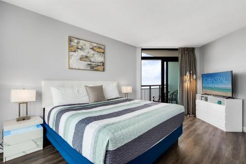 a bedroom with a large bed and a television at Fabulous Angled Oceanfront Suite! CR1701 in Myrtle Beach