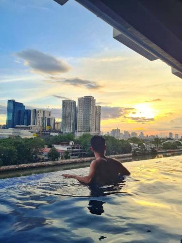 a man in a swimming pool in a city at The Hmlet Manila, Near Poblacion Makati Nightlife in Manila