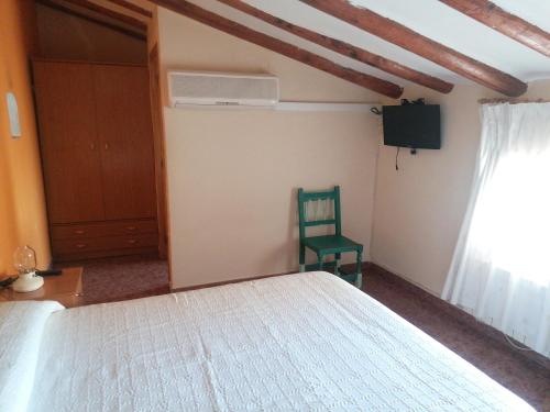 Un dormitorio con una cama blanca y una silla verde. en Casa Gil, en Loporzano
