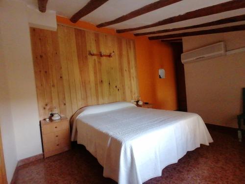 Un dormitorio con una cama blanca y una pared de madera. en Casa Gil, en Loporzano