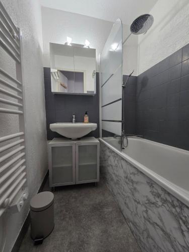 une salle de bain avec un lavabo et une baignoire dans l'établissement Appartement chaleureux, à Risoul