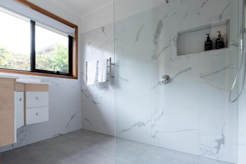 a bathroom with a shower with white marble walls at Bright and Beautiful Near the Gorge with Parking in Royal Park