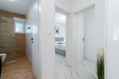 a white bathroom with a bed and a shower at Apartment Cvit in Trogir