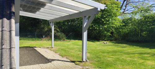eine weiße Pergola an der Seite eines Hauses in der Unterkunft Ferienhaus Ostseeküste in Damp