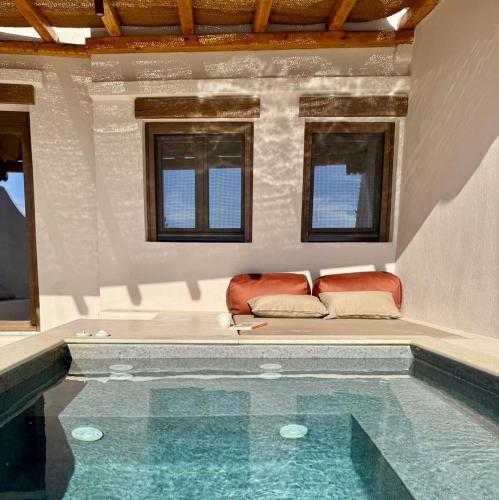 a swimming pool with a couch in a room with windows at Conte Mykonos II in Aggelika