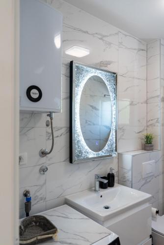 a white bathroom with a sink and a mirror at Apartment Cvit in Trogir