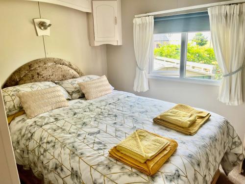 a bedroom with a bed with two towels on it at Station House Caravan in Innerwick