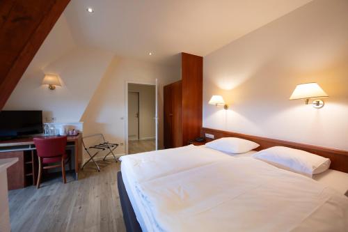 a bedroom with a large white bed and a desk at L'Hôtel et Restaurant du Golf de Clervaux in Eselborn