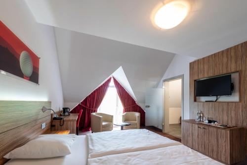 a bedroom with a large bed and a tv at L'Hôtel et Restaurant du Golf de Clervaux in Eselborn