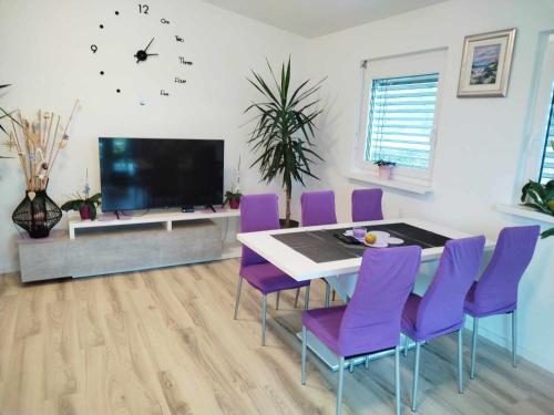 a dining room with a table and purple chairs at Holiday house Zala in Puconci