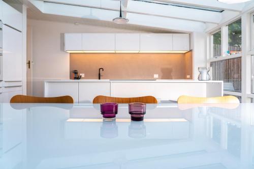 a kitchen with white cabinets and purple chairs at Strandhytten in Ålsgårde