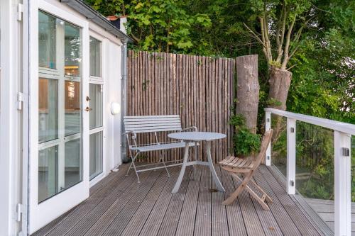 a patio with a table and chairs on a deck at Strandhytten in Ålsgårde