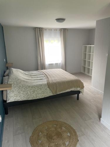a bedroom with a bed and a window and a rug at Gîte à la campagne in L'Etang-Bertrand