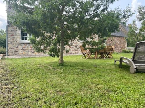 a tree in a yard with a table and benches at Gîte à la campagne in L'Etang-Bertrand