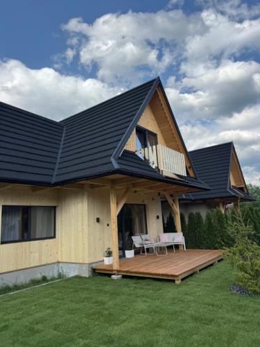 a house with a black roof and a deck at Stylowa Chata in Zakopane