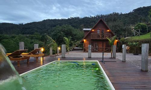a house with a swimming pool next to a wooden deck at Chalé Familiar com Jacuzzi e Piscina in Tubarão