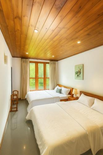 a bedroom with three beds and a wooden ceiling at Sweet Villa Hotel in Peradeniya