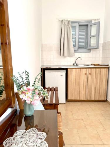 a kitchen with a table with a vase of flowers at Kirki Rooms on the Hill in Parikia