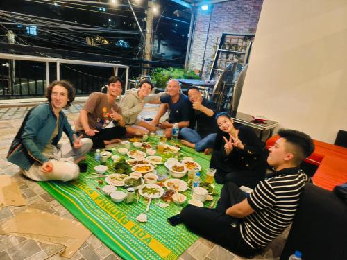 een groep mensen die rond een tafel zitten met eten bij BIKA Hostel and Dorm in Da Lat